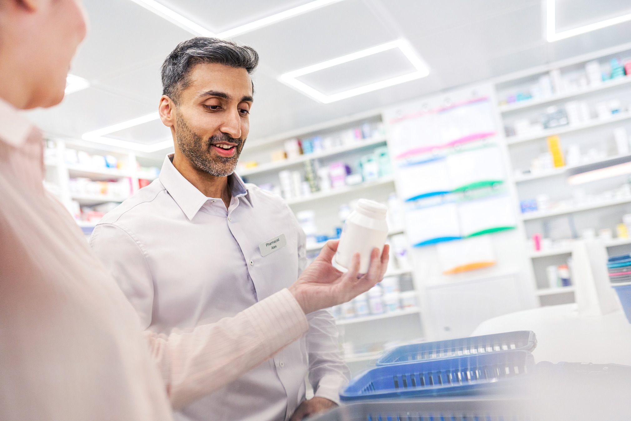 Pharmacy employee showing a medication to a colleague.