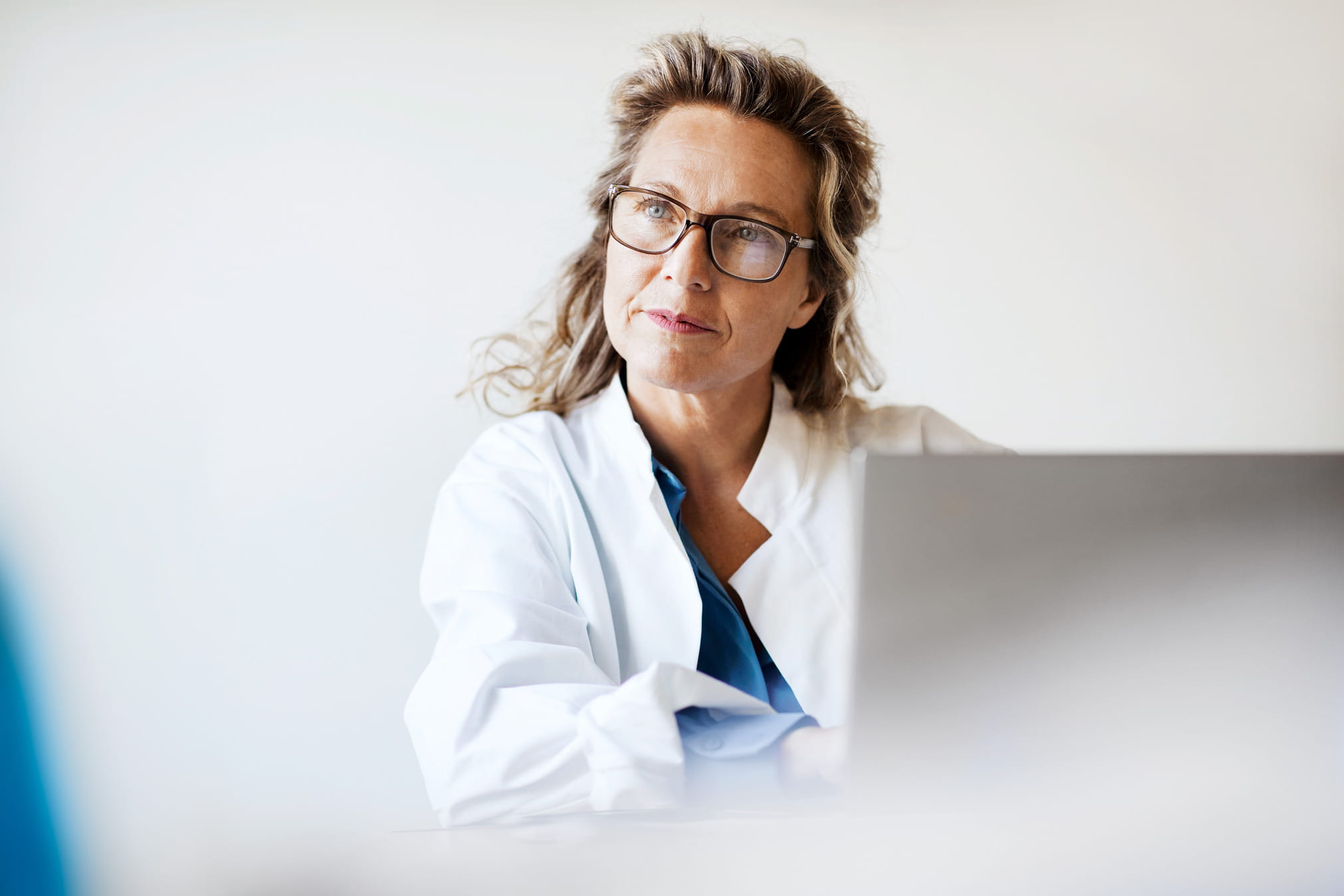 Doctor looking up from laptop in a bright office room