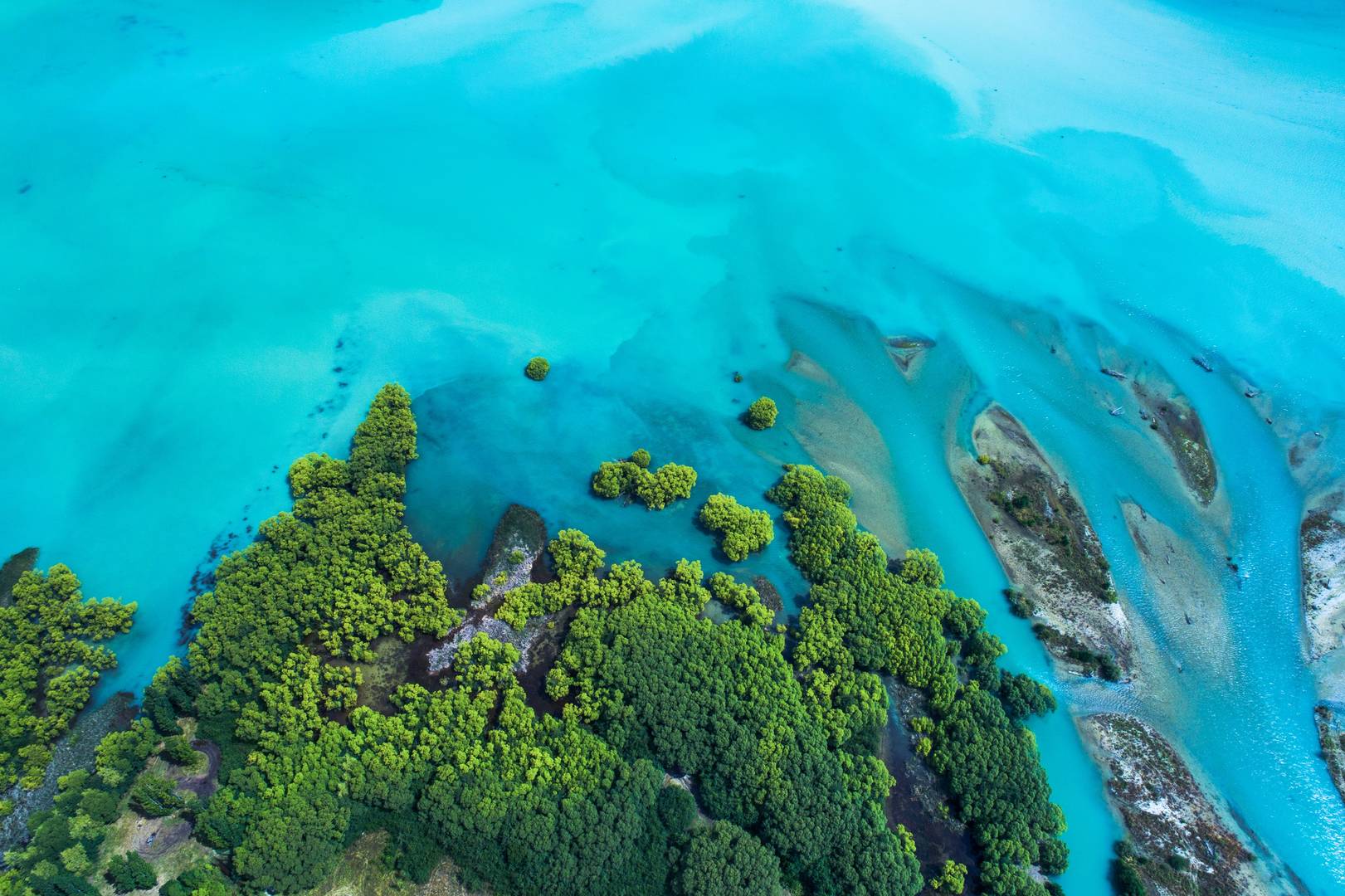 Aerial image of green land against a bright blue ocean.