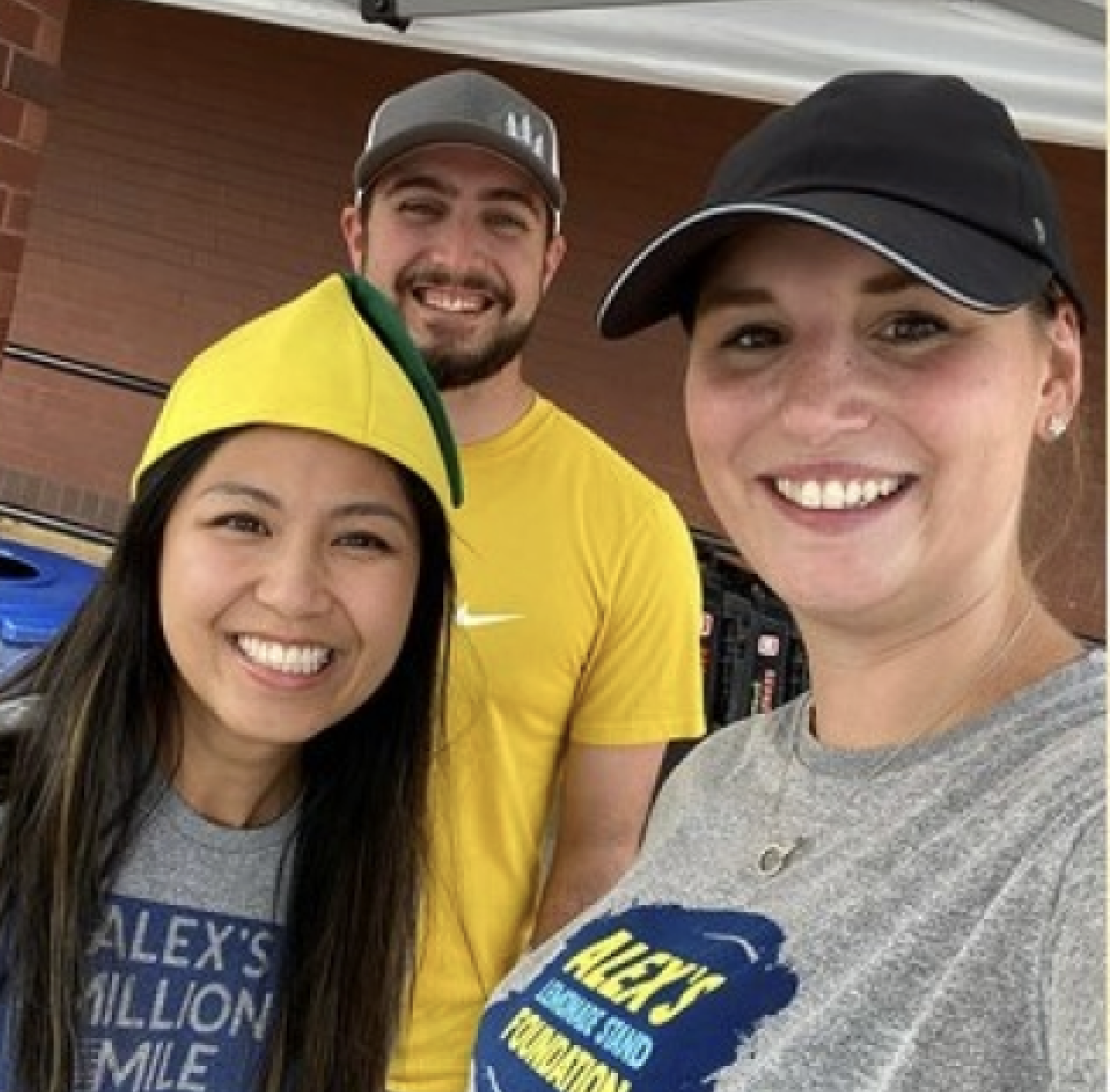 Trois bénévoles sourient à la caméra tout en portant des chemises pour Alex's Lemonade Stand.