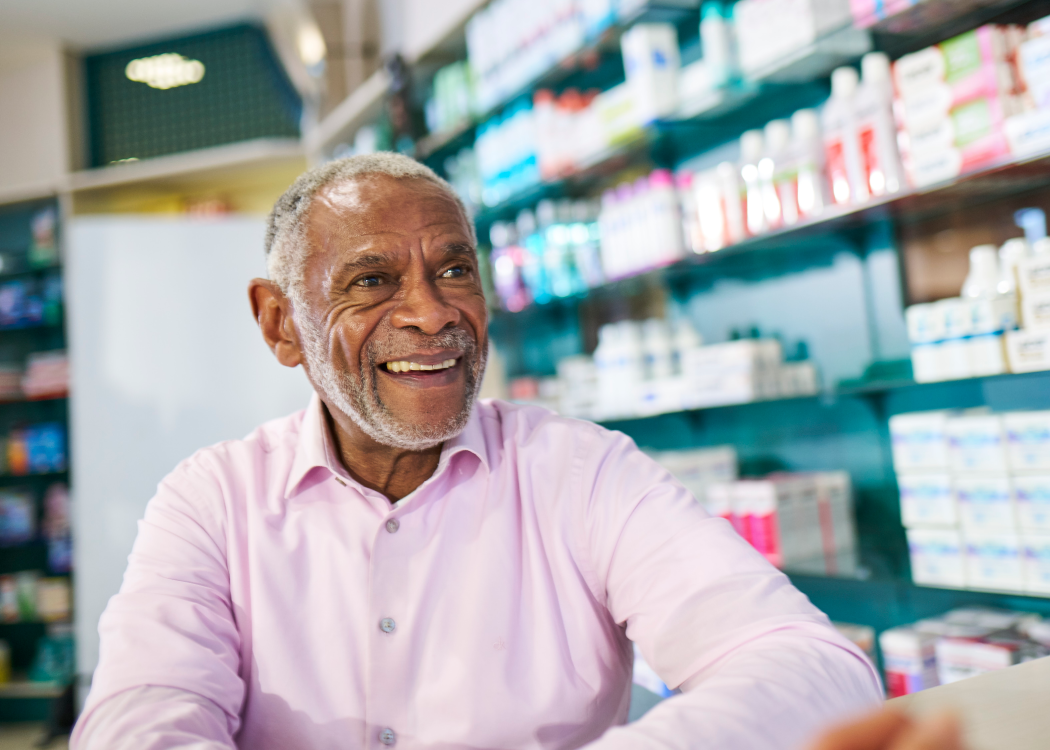 Un homme âgé sourit alors qu’il est assis devant des étagères remplies de fournitures médicales.
