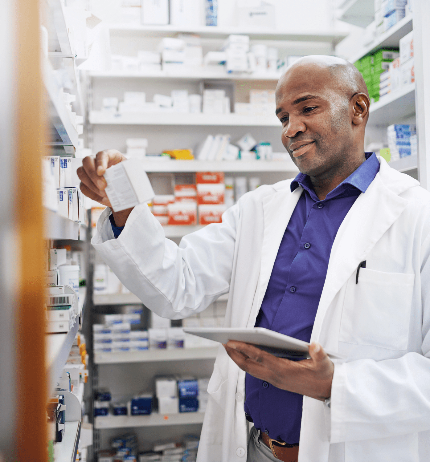 A pharmacist examines a medication while holding a tablet.