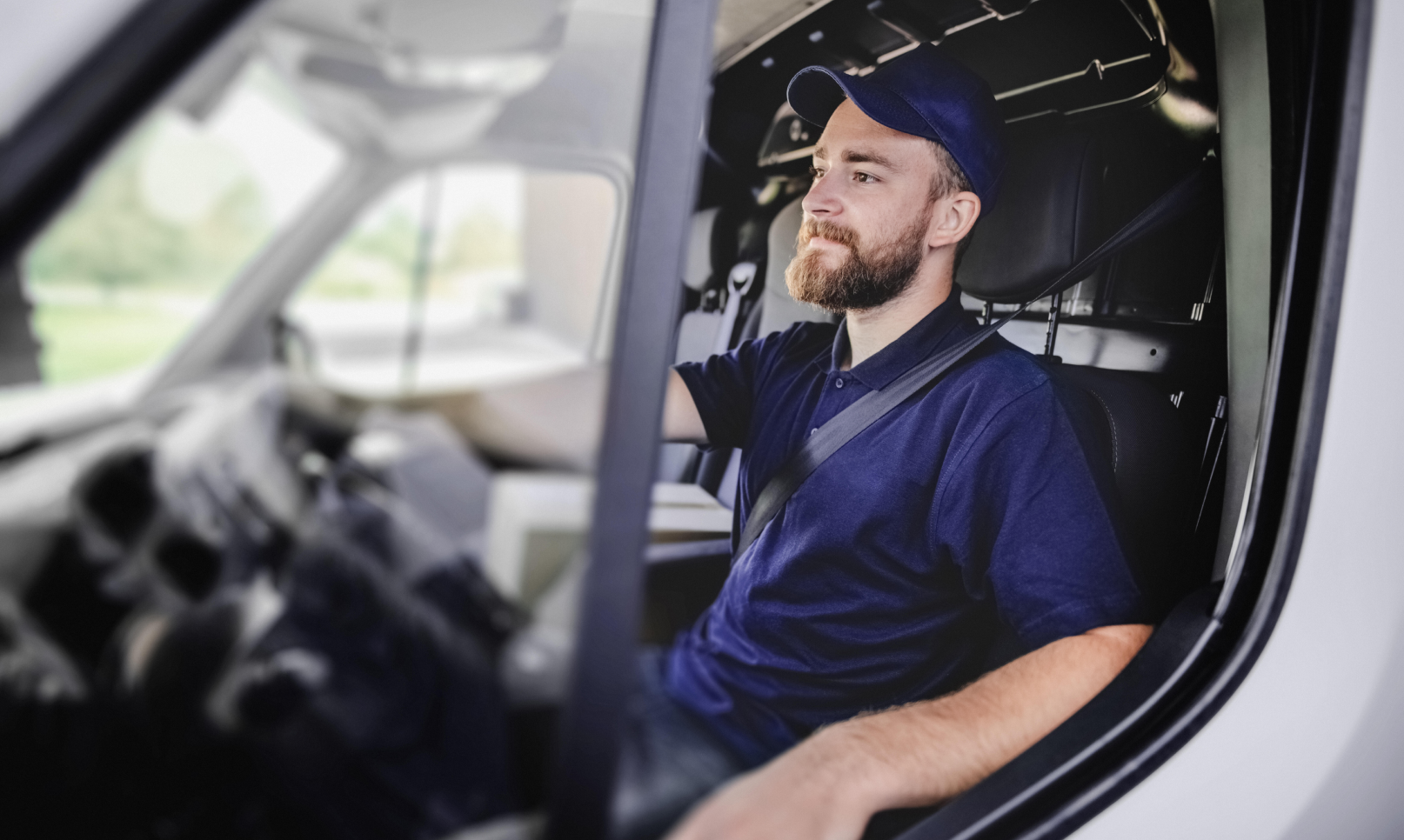 Un repartidor con una gorra de béisbol sentado en su furgoneta.