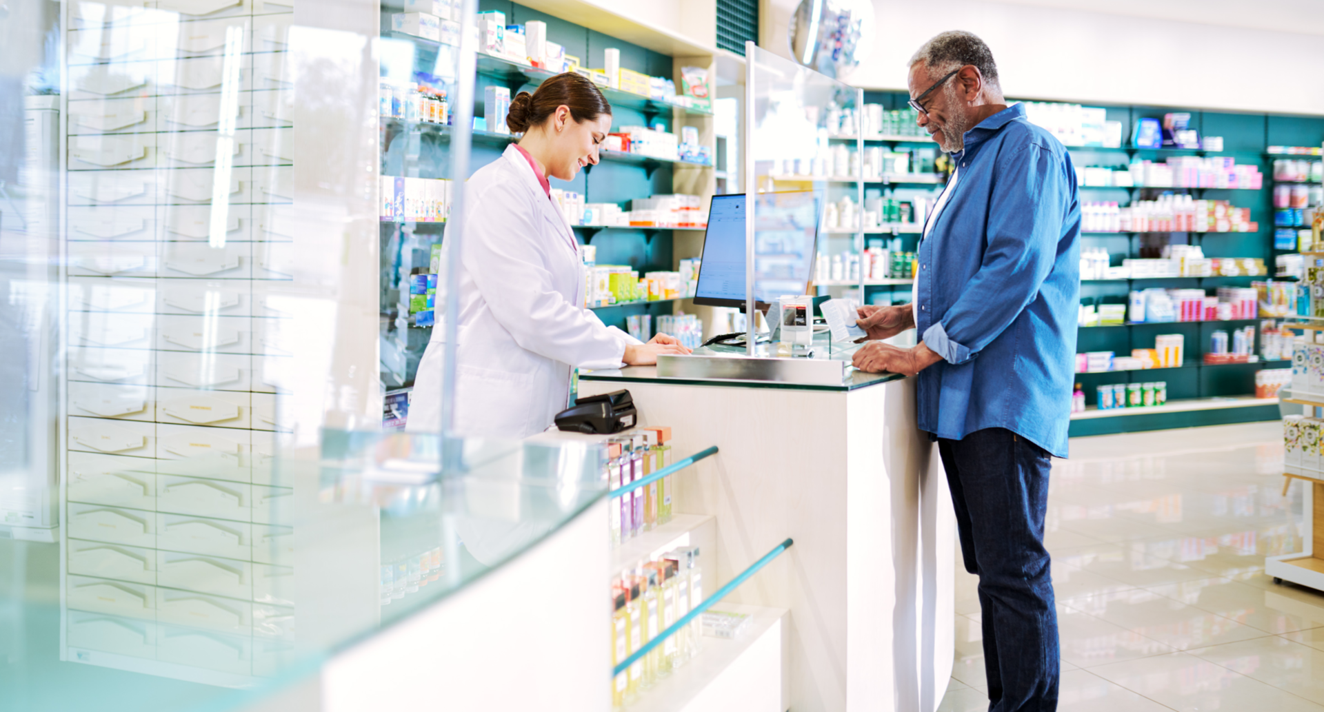 Un pharmacien aide un homme au comptoir d’une pharmacie.