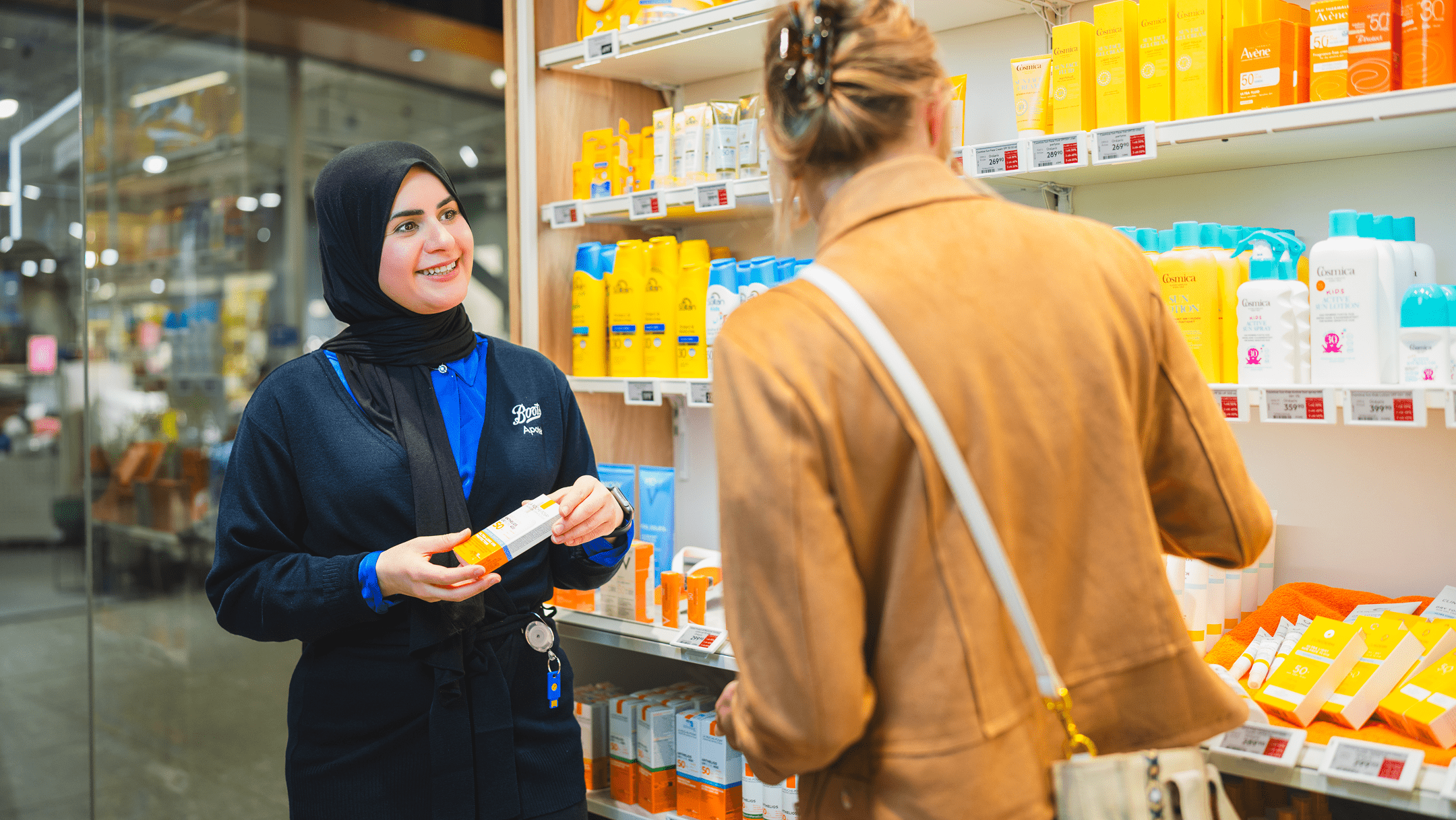 Smiling pharmacy employee assisting a customer in finding the right product.