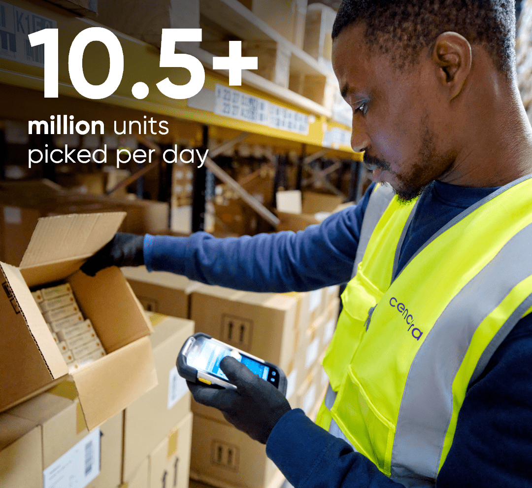 A man wearing a yellow vest is scanning boxes in a distribution center.