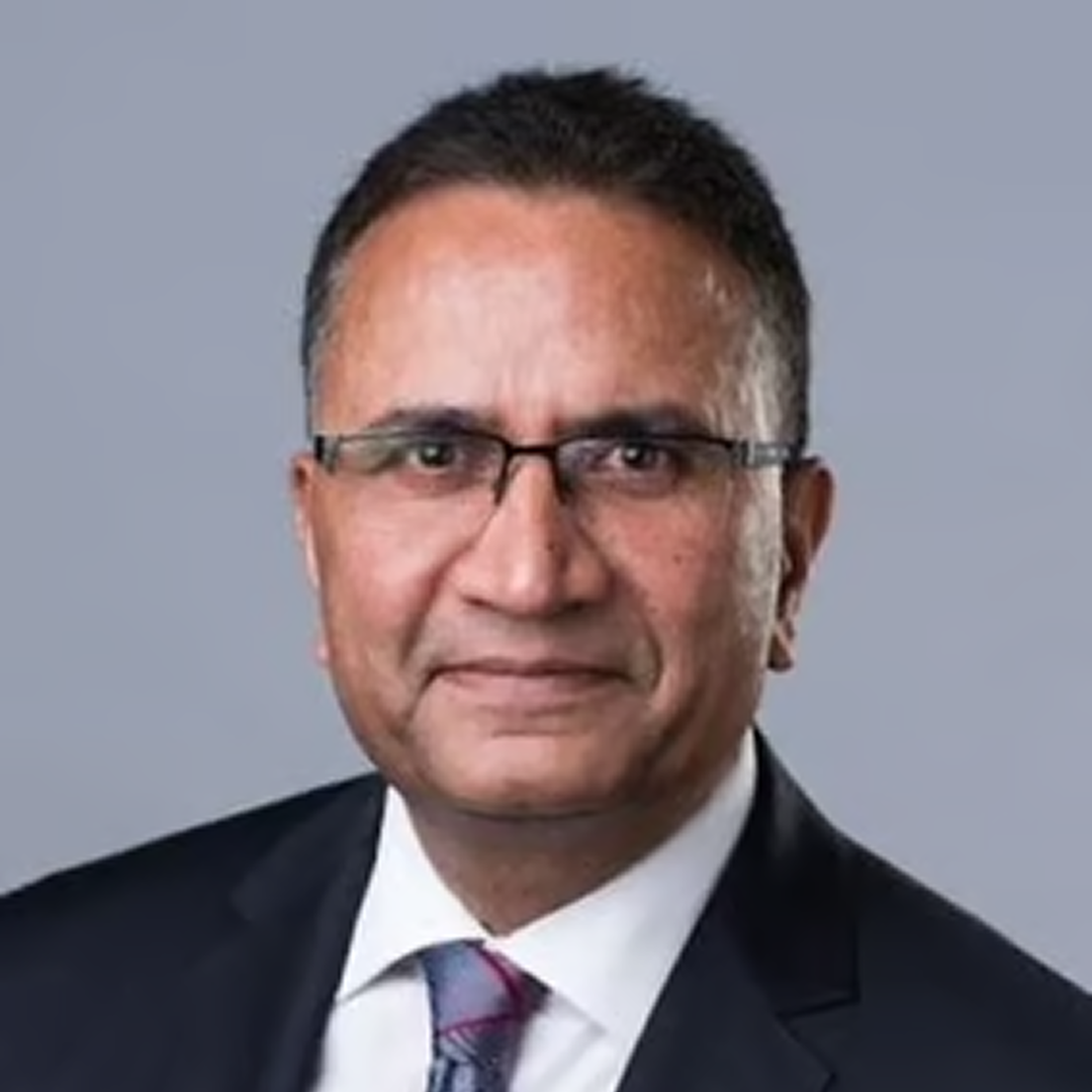  A headshot of a Vice President at Cencora, a late middle aged man with short black hair, rectangular prescription glasses, and a slight smile, dressed in a blue suit and tie conveying leadership and professionalism.