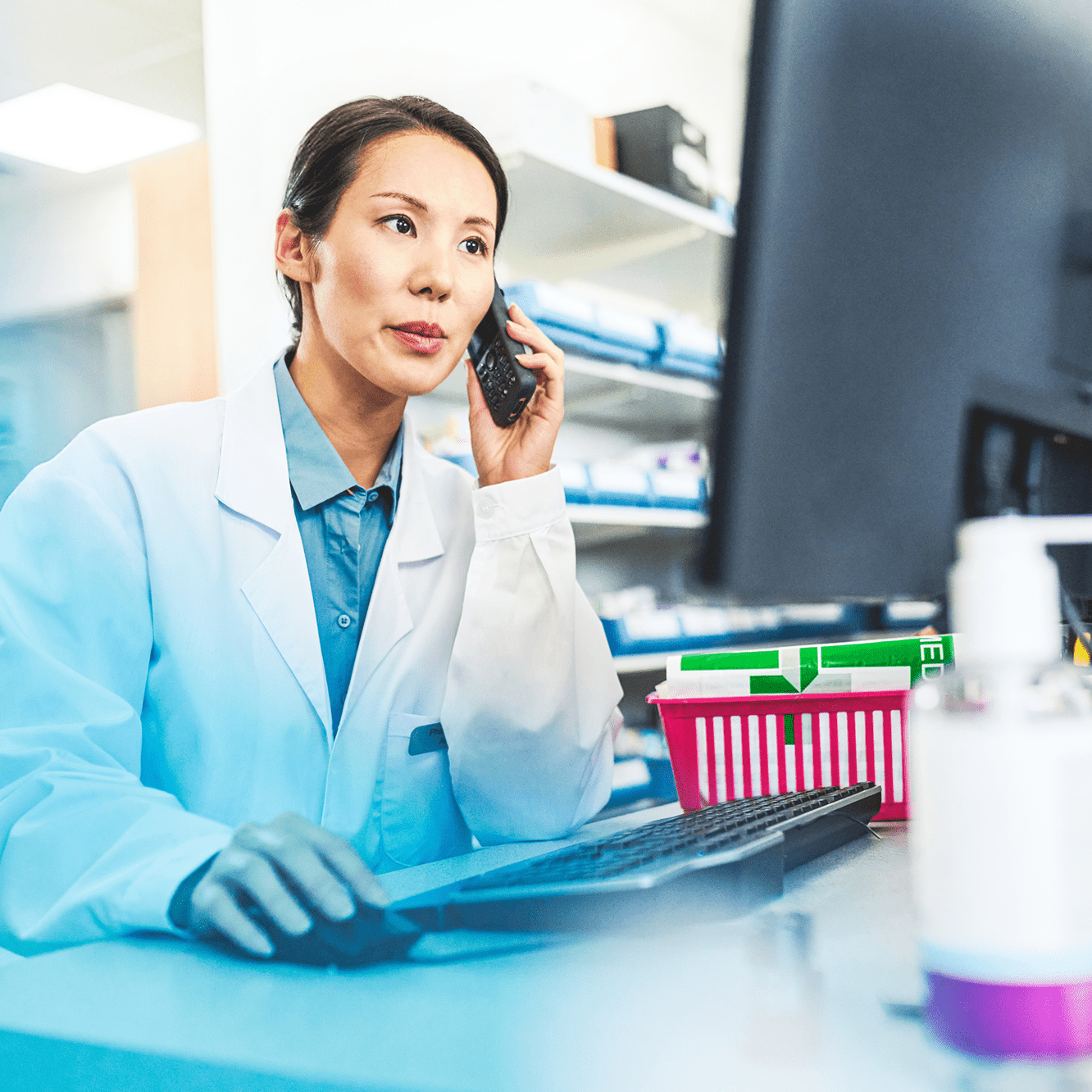 Pharmacist working in front of a monitor while speaking on the phone