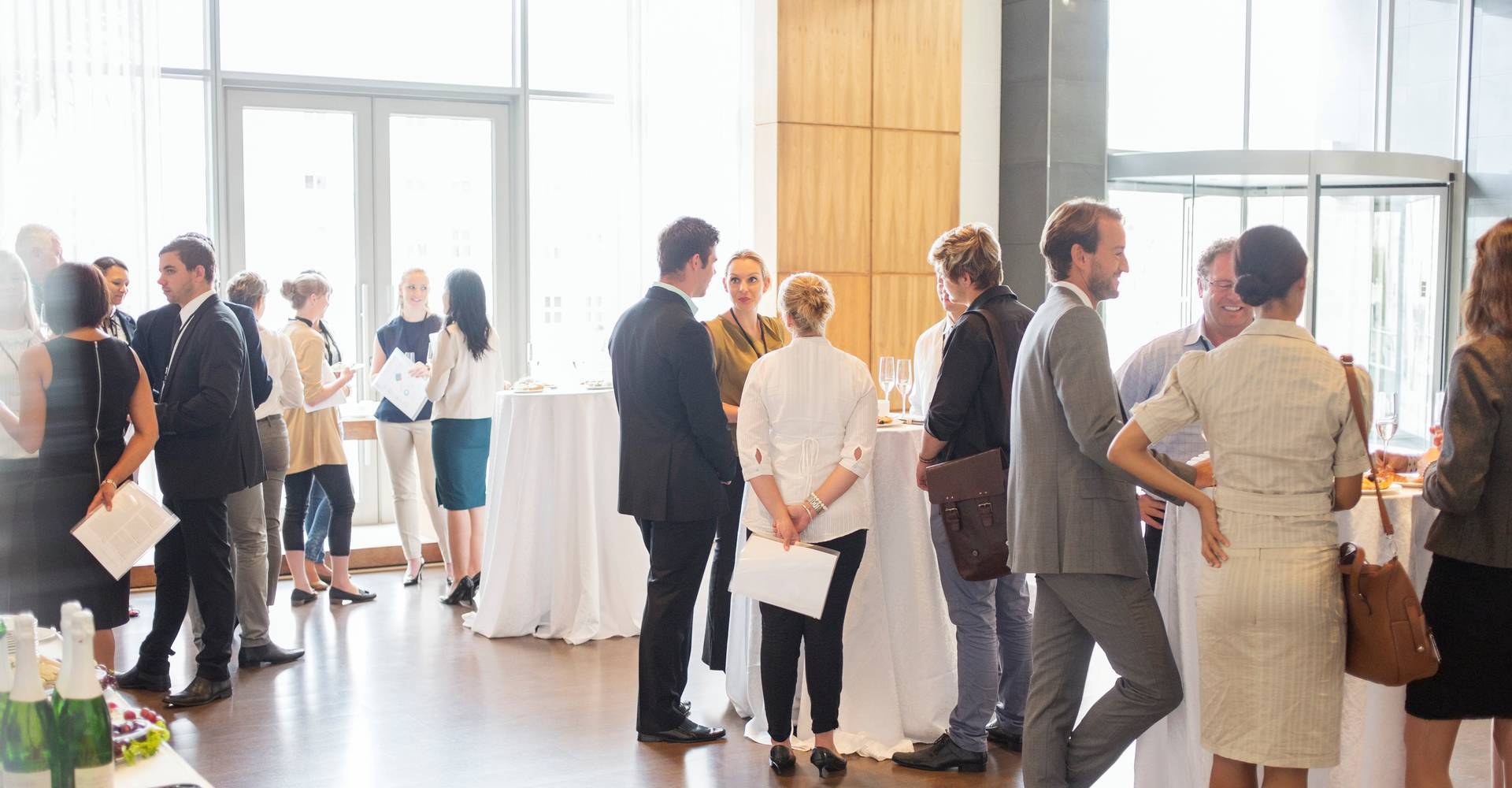 Group of conference participants standing in lobby of conference center, socializing during lunch break