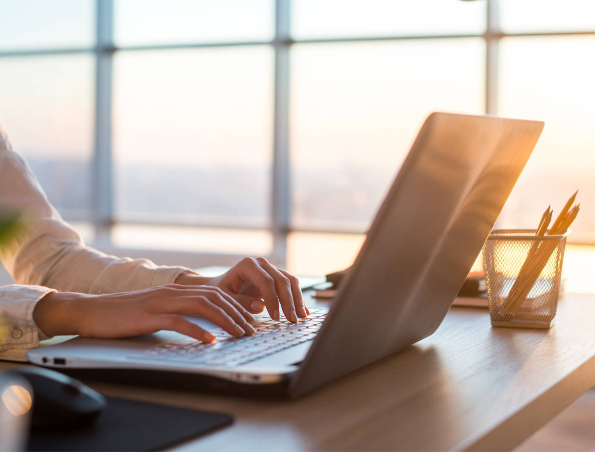 person's hands typing on laptop