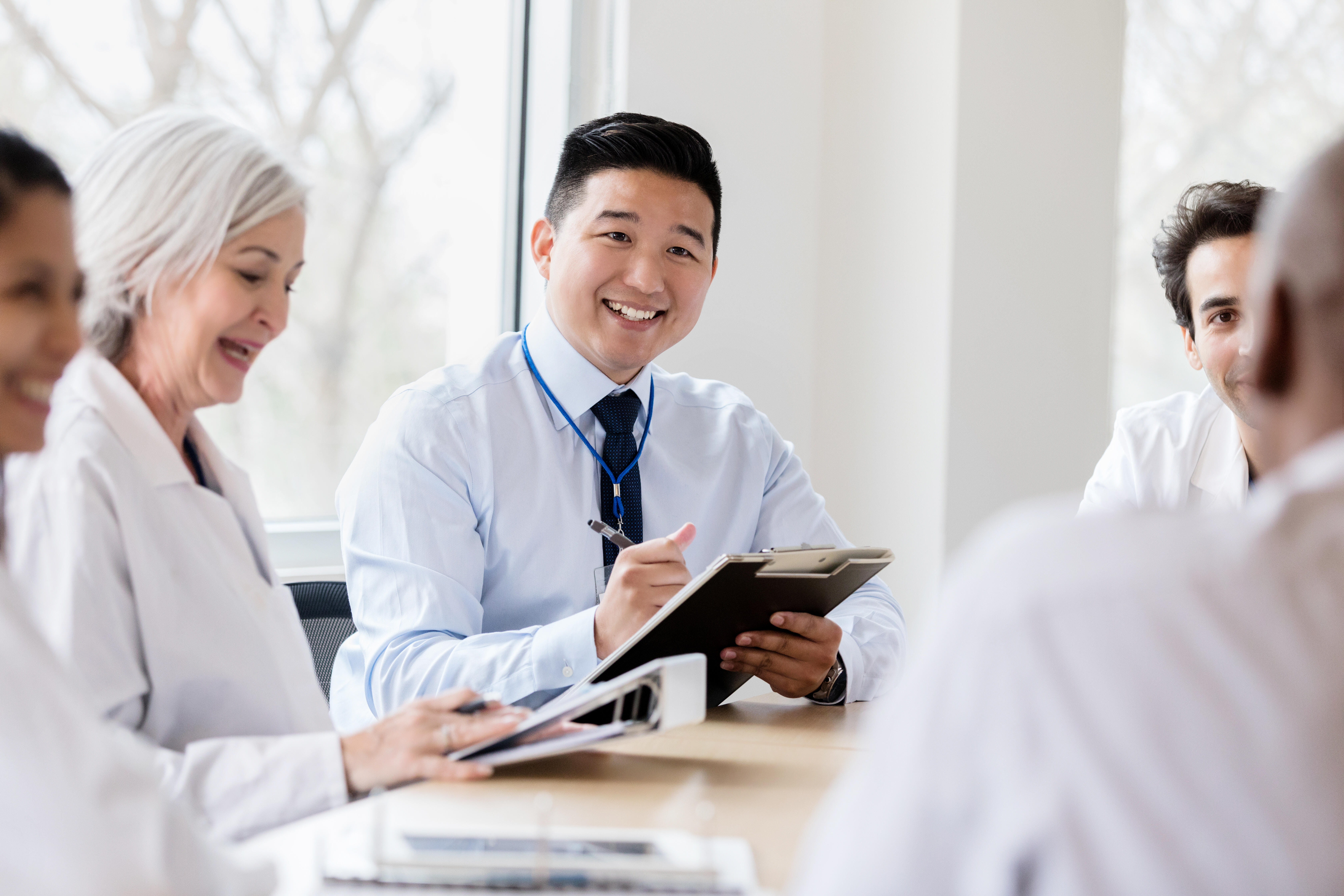 Smiling businessman holding a tablet and taking notes during the meeting