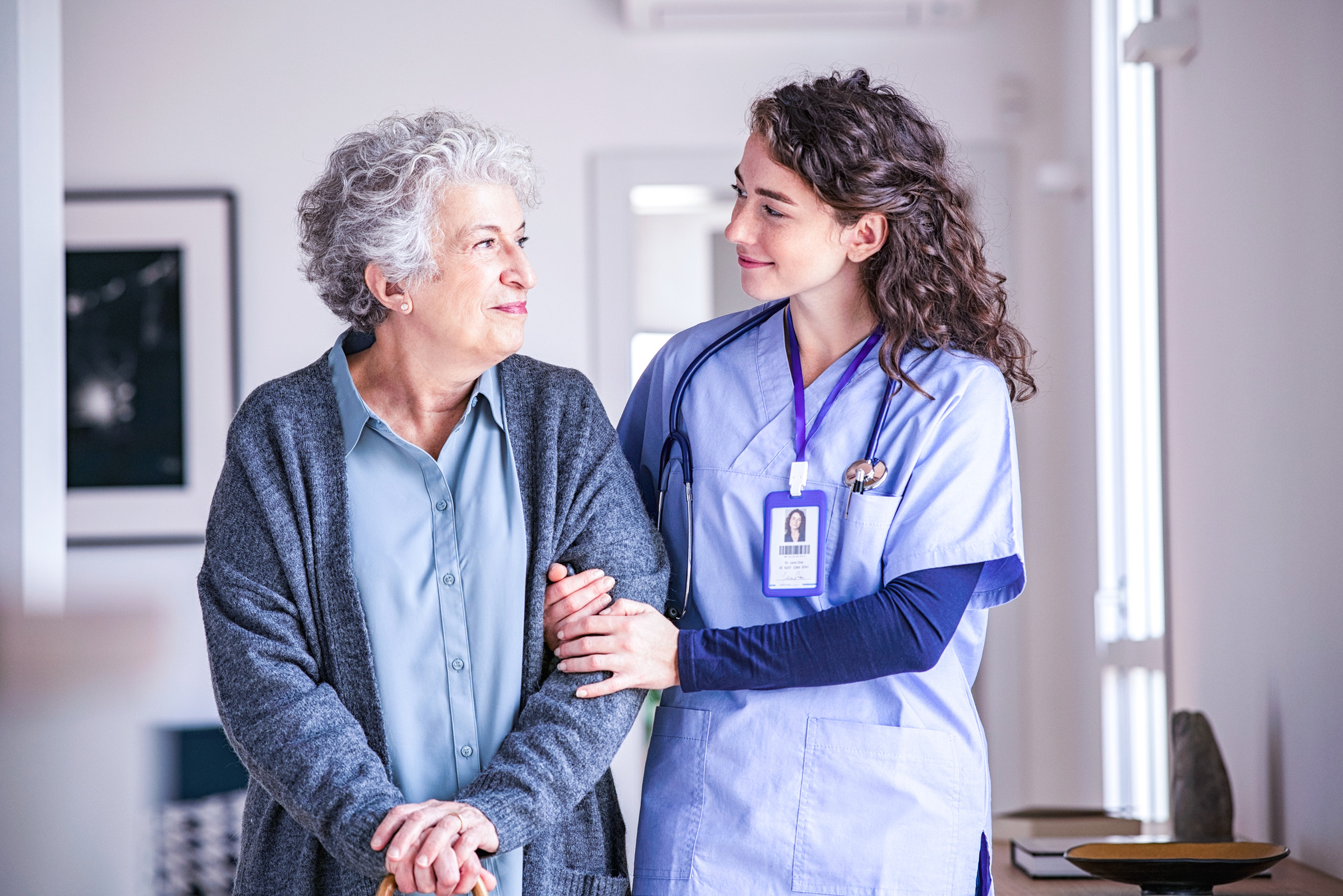 Young female nurse supports a elderly woman.