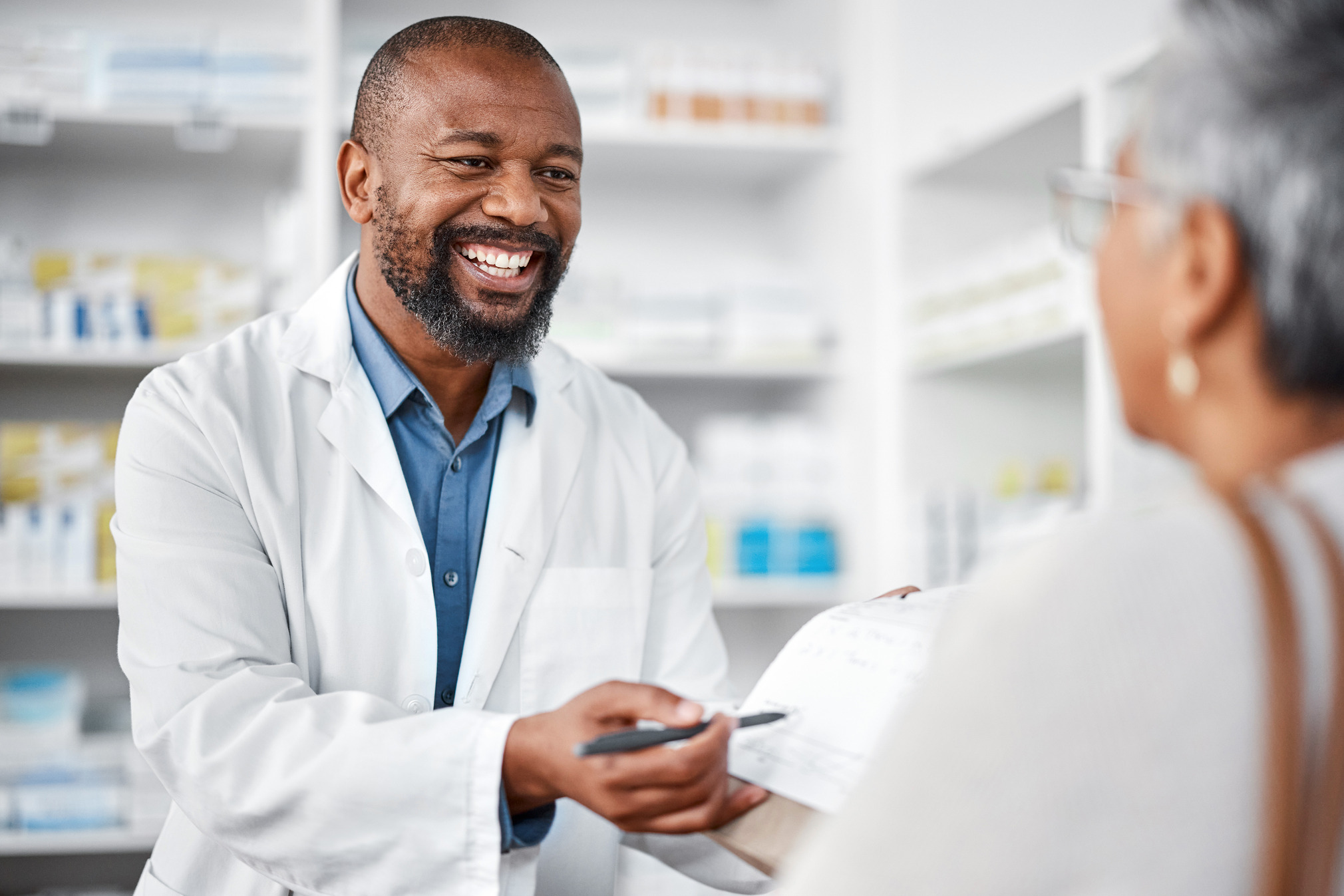 Smiling pharmacist serving a patient.